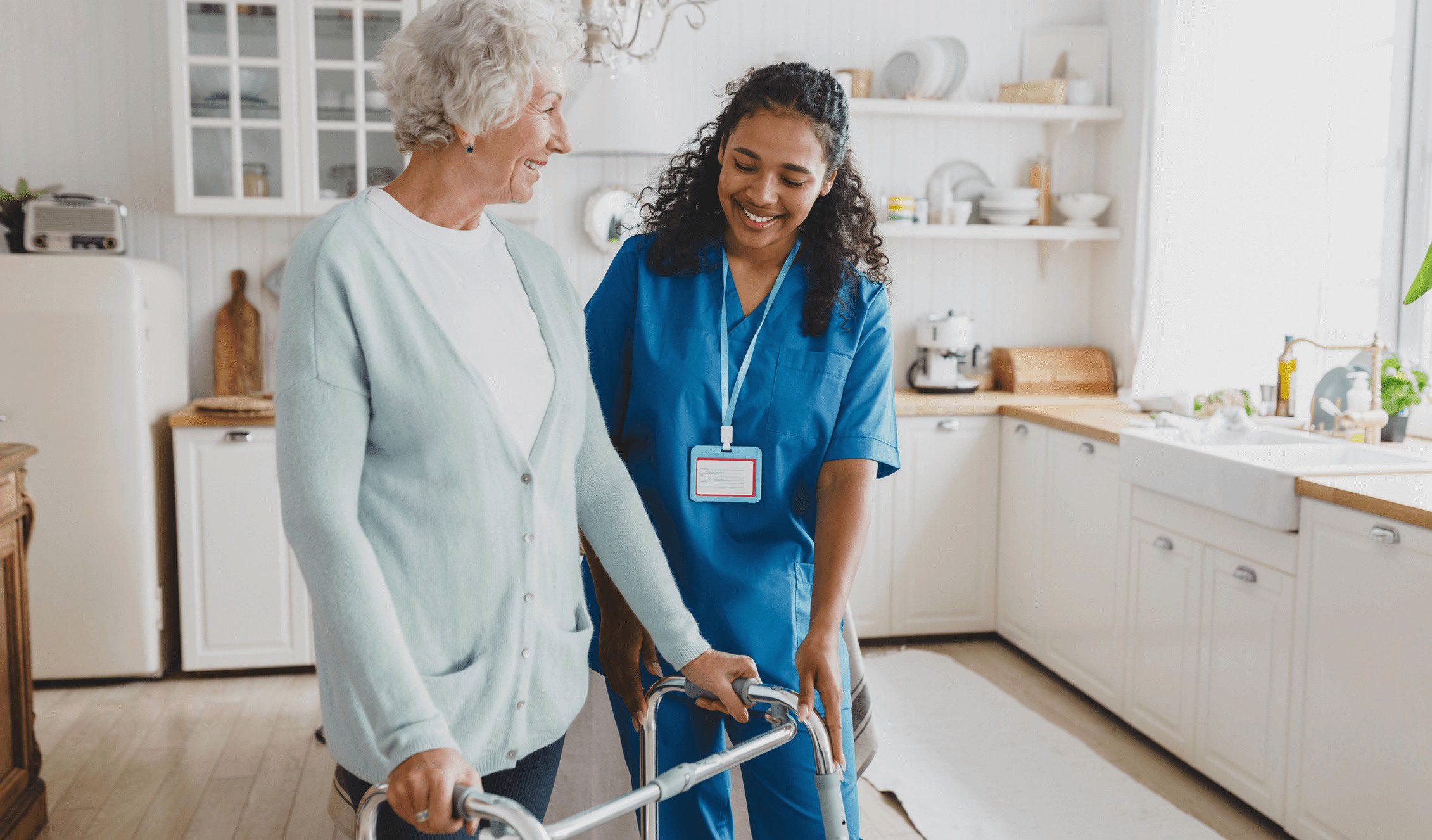 GettyImages-2174052664 3 (1) A nurse helping an elderly woman walk with her walker.