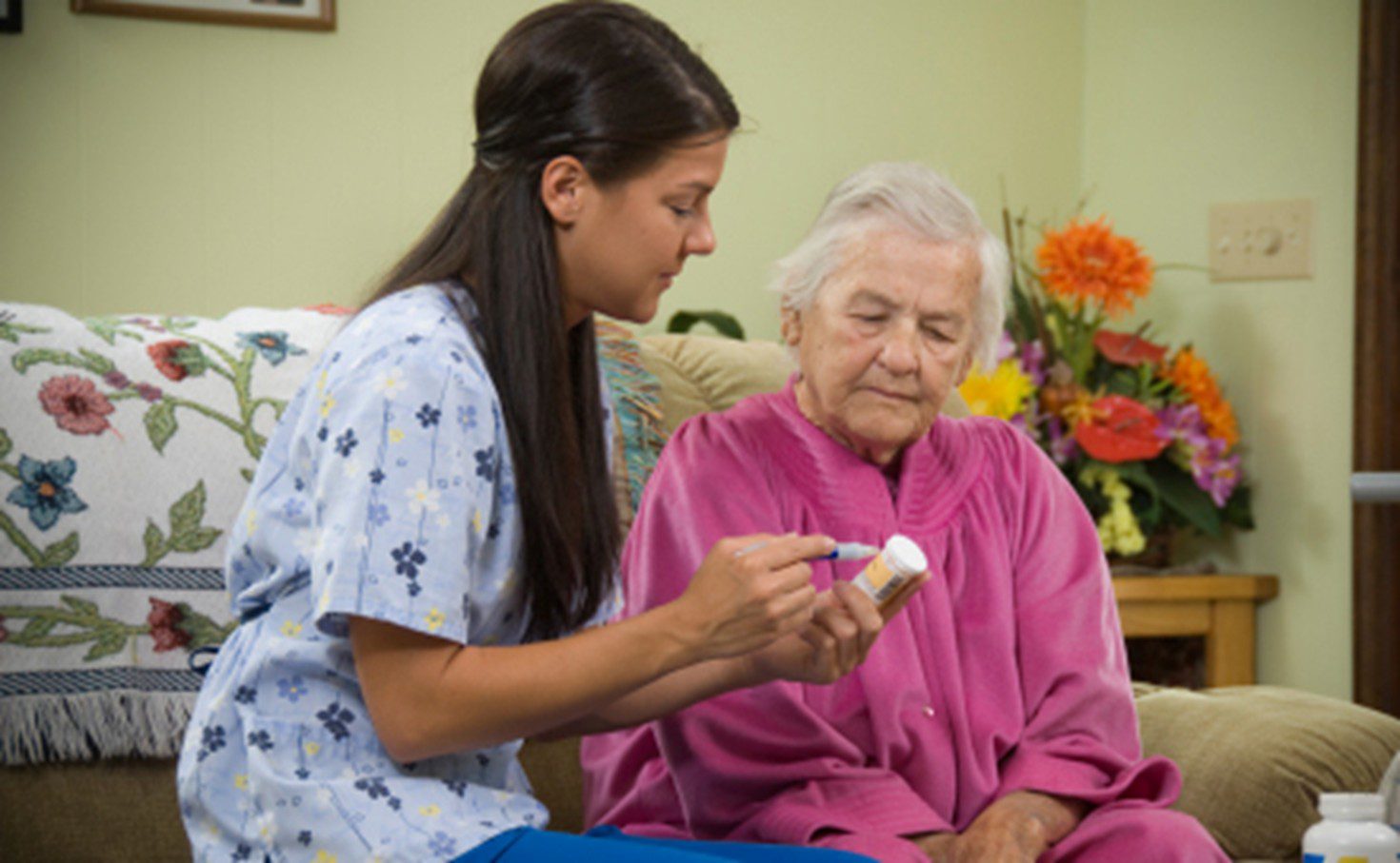 A woman is helping an older person with her medicine.