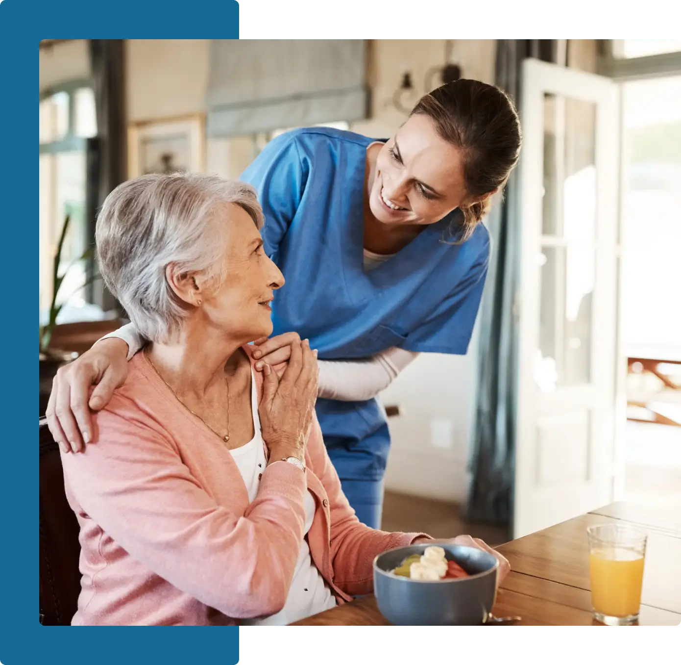 A nurse and an elderly woman sitting at a table.