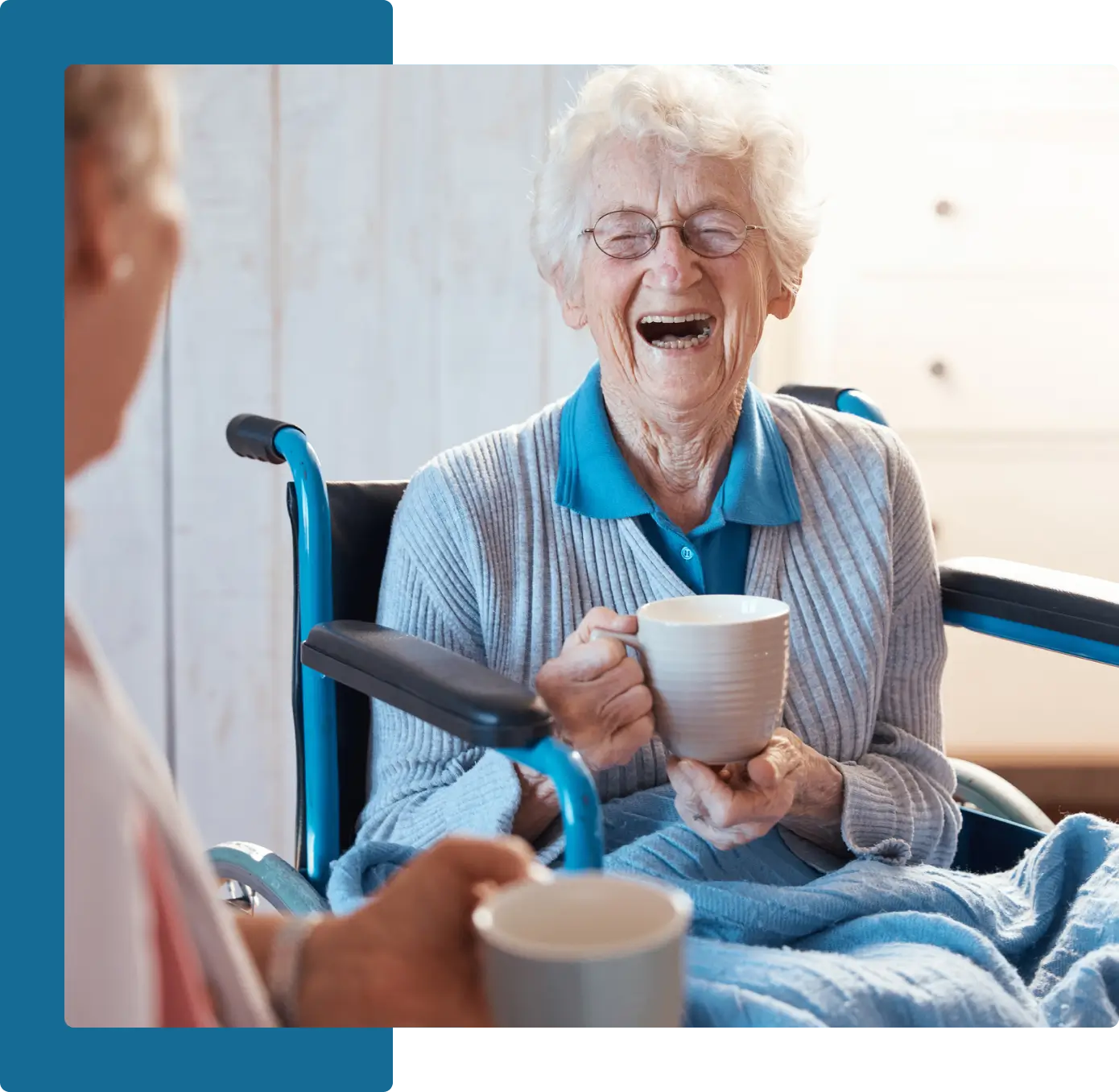 A woman sitting in a wheelchair holding a cup.